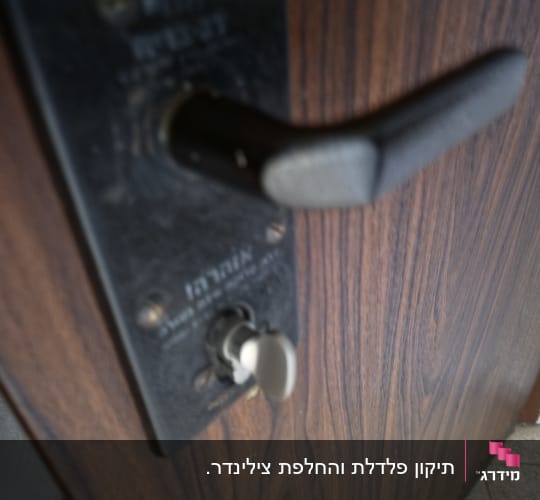 ידית ומנעול של דלת ממ"ד על גבי דלת דמוית עץ